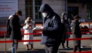 A man reads a book while waiting in a line to undergo coronavirus disease (COVID-19) test at a coronavirus testing site which is temporarily set up in front of a railway station on Christmas day in Seoul, South Korea, December 25, 2020. REUTERS/Kim Hong-J