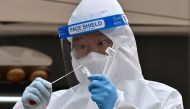 A medical staff member wearing protective gear takes a swab from a visitor to test for the Covid-19 coronavirus at a temporary testing station outside the City Hall in Seoul on December 28, 2020. / AFP / Jung Yeon-je