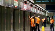 Workers wipe down doors at a train station during the coronavirus disease (COVID-19) outbreak in Singapore August 17, 2020. REUTERS/Edgar Su/File Photo
