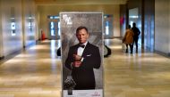 Shoppers walk past an advertisement for the upcoming James Bond film 