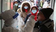 A medical worker in protective suit collects a swab from a resident following a recent coronavirus disease outbreak in Shijiazhuang, Hebei province, China January 6, 2021. China Daily via Reuters