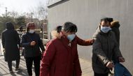 People wearing face masks walk along a street, following new cases of the coronavirus disease (COVID-19) in the country, in Beijing, China January 11, 2021. REUTERS/Tingshu Wang