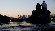 Men sit on a rock as they look at the giant Olympic rings, amid the coronavirus disease (Covid-19) outbreak, in Tokyo, Japan, January 13, 2021. Reuters/Kim Kyung-Hoon