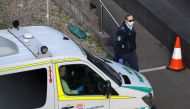 File photo: A police officer watches an entrance to a quarantine hotel, where returning travelers are kept in isolation for a period to curb the spread of the coronavirus disease (COVID-19), as a patient transport service vehicle departs in Sydney, Austra