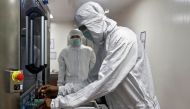 An employee in personal protective equipment (PPE) removes vials of AstraZeneca's COVISHIELD, coronavirus disease (COVID-19) vaccine from a visual inspection machine inside a lab at Serum Institute of India, Pune, India, November 30, 2020. REUTERS/Francis