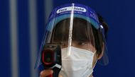 An event staff wearing a protective mask and a face shield checks the temperature of visitors at the Wearable Expo, amid the coronavirus disease (COVID-19) outbreak, at an exhibition center in Tokyo, Japan, January 20, 2021. REUTERS/Kim Kyung-Hoon