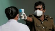 A health official uses a thermometer to take the temperature of a healthcare worker during a simulation exercise for the coronavirus disease (COVID-19) vaccination in the Piliyandala suburb, south of Colombo, Sri Lanka January 23, 2021.REUTERS/Dinuka Liya