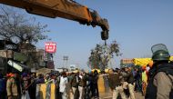 Police officers, with the help of a crane, put a barricade at the site of a protest where farmers are protesting against farm laws, at Singhu border, in New Delhi, India, January 27, 2021. REUTERS/Anushree Fadnavis
