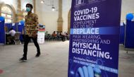 A man walks past an awarness sign inside the Khaliq Dina Hall and Library, which has been converted to be used as a vaccination centre, to administering coronavirus disease (COVID-19) vaccine, in Karachi, Pakistan February 1, 2021. REUTERS/Akhtar Soomro

