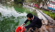 A man releases carps to Hoan Kiem lake on Kitchen God's Day as part of the traditional Vietnamese Lunar New Year celebrations, the biggest festival of the year in Hanoi, Vietnam February 4, 2021. REUTERS/Kham