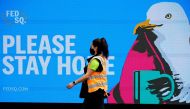 An essential worker walks past a 'Please Stay Home' sign on the first day of a five-day lockdown implemented in the state of Victoria in response to a coronavirus disease (COVID-19) outbreak in Melbourne, Australia, February 13, 2021. REUTERS/Sandra Sande