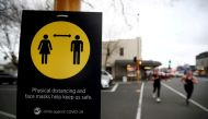 People jog past a social distancing sign on the first day of New Zealand's new coronavirus disease (COVID-19) safety measure that mandates wearing of a mask on public transport, in Auckland, New Zealand, August 31, 2020. REUTERS/Fiona Goodall/File Photo