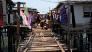 A woman washes clothes on a wooden path between stilt houses at Hanuabada Village, located in Port Moresby Harbour, Papua New Guinea, November 19, 2018. Picture taken November 19, 2018. REUTERS/David Gray/File Photo