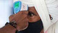 A health worker uses an infrared thermometer to check the temperature of a passenger amid the spread of the coronavirus disease (COVID-19), at a railway station in Mumbai, India, March 21, 2021. REUTERS/Francis Mascarenhas