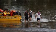 People wade through floodwaters resulting from prolonged rains northwest of Sydney in Wisemans Ferry, Australia, March 25, 2021. REUTERS/Loren Elliott