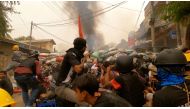 Protesters use slingshots while taking cover behind a barricade as smoke rises from burning debris during ongoing protests against the military coup, in Monywa, Sagaing region, Myanmar March 29, 2021 in this still image from video obtained by REUTERS 
