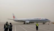 File photo: Staff members stand near a Boeing 737-800 airplane of Air China on the tarmac of Beijing Capital International Airport, which is shrouded in dust as the city is hit by a sandstorm, in Beijing, China March 28, 2021. Reuters/Carlos Garcia Rawlin
