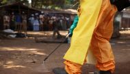 A member of the French Red Cross disinfects the area around a motionless person suspected of carrying the Ebola virus as a crowd gathers in Forecariah, Guinea, January 30, 2015. REUTERS/Misha Hussain/File Photo