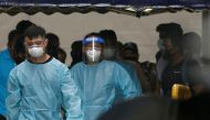 Personnel in protective garment usher a group of migrant workers to take a bus to a government quarantine facility after workers were tested positive for the coronavirus disease (COVID-19) at Westlite Woodlands dormitory in Singapore April 22, 2021. REUTE
