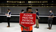A worker holds a sign to remind visitors to practice social distancing at a coronavirus disease (COVID-19) vaccination centre in Kuala Lumpur, Malaysia May 5, 2021. REUTERS/Lim Huey Teng