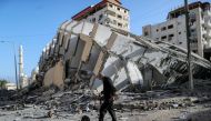 A Palestinian man walks past the remains of a tower building which was destroyed in Israeli air strikes, amid a flare-up of Israeli-Palestinian violence, in Gaza City May 12, 2021. REUTERS/Suhaib Salem