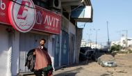 A Palestinian man carrying clothes walks as he evacuates his shop following Israeli air strikes, amid a flare-up of Israeli-Palestinian violence, in Gaza City May 12, 2021. REUTERS/Mohammed Salem