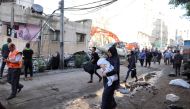 People walk past debris in a street at the site of Israeli air strikes, in Gaza City May 16, 2021. REUTERS/Mohammed Salem