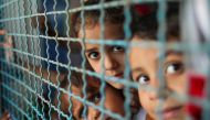Palestinian children, who fled their homes due to Israeli air and artillery strikes, look through a window fence at a United Nations-run school where they take refuge, in Gaza City May 18, 2021. REUTERS/Suhaib Salem