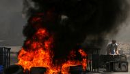 A Palestinian demonstrator sets up a barricade as tires burn during a protest over tension in Jerusalem and Israel-Gaza escalation, in Hebron in the Israeli-occupied West Bank, May 14, 2021. REUTERS/Mussa Qawasma