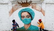 Children run past coronavirus-themed graffiti depicting a medic outside Saint Petersburg, Russia November 14, 2020. REUTERS/Anton Vaganov
