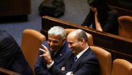 Prime Minister Naftali Bennett chats with Foreign Minister Yair Lapid, following the vote for the new coalition at the Knesset, Israel's parliament, in Jerusalem June 13, 2021. Reuters/Ronen Zvulun