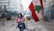 FILE PHOTO: A demonstrator carries a national flag along a blocked road, during a protest against the fall in Lebanese pound currency and mounting economic hardships, near the Central Bank building, in Beirut, Lebanon March 16, 2021. REUTERS/Mohamed Azaki