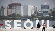 A woman wearing a mask amid the coronavirus disease (COVID-19) pandemic takes photographs of her boyfriend at a Han river park in Seoul, South Korea, May 24, 2021. Reuters/Kim Hong-Ji/File Photo