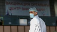 A vendor wearing a protective face mask waits for customers near an information banner placed outside the coronavirus disease (COVID-19) vaccination centre at a food market in Almaty, Kazakhstan April 14, 2021. Picture taken April 14, 2021. REUTERS/Pavel 