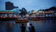 People sit on the banks of the Singapore River at Clarke Quay in Singapore April 14, 2018. REUTERS/Thomas White/File Photo