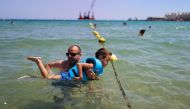 Disabled Max Segui, 7, accompanied by his father Albert Segui, 43, wears a life jacket as they swim in the Mediterranean sea, on Barcelona's Nova Icaria Beach, Spain, July 17, 2021. REUTERS/Nacho Doce