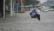 A resident wearing a rain cover stands on a flooded road in Zhengzhou, Henan province, China July 20, 2021. (cnsphoto via REUTERS)