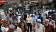 FILE PHOTO:A man wears a protective face mask as he walks among other people along a street, as the outbreak of the coronavirus disease (COVID-19) continues, in Karachi, Pakistan June 16, 2020. REUTERS/Akhtar Soomro