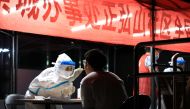 A medical worker in protective suit collects a swab from a resident for nucleic acid testing following new cases of the coronavirus disease (COVID-19) in Zhengzhou, Henan province, China early August 2, 2021. cnsphoto via Reuters 