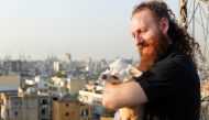 Shady Rizk, a survivor wounded during last year's Beirut port blast, holds his dog on the rooftop of his house, in Sin el-Fil, Lebanon July 30, 2021. REUTERS/Aziz Taher
