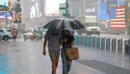 People walk through falling rain in Times Square as Tropical Storm Henri affects the region in Manhattan, New York City, U.S., August 23, 2021. REUTERS/Andrew Kelly
