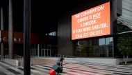 A man pulling a cart with his belongings walks past a billboard outside the Ernest N. Morial Convention Center ahead of Hurricane Ida, in New Orleans, Louisiana, U.S. August 29, 2021. REUTERS/Marco Bello

