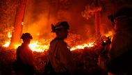 Matt Ziebarth (center), 45, a fire fighter with the El Dorado County Fire Department, and his colleagues, Darob Baker (left), 30, and fire captain Rob Sime, 44, work on structure protection along Santa Clause Drive as flames from the Caldor Fire burn thro