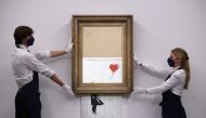 A gallery assistant poses by 'Love is in the Bin', an artwork by Banksy, which will be for sale in an auction, at Sotheby's in London, Britain, September 3, 2021. REUTERS/Tom Nicholson
