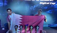 Khalid Al Maraghi and Faesal Al Yafei pose with the Qatari flag and their trophies.