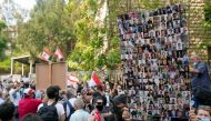 A demonstrator carries pictures of the victims of the 2020 Beirut port blast during a protest in front of the Justice Palace after a probe into the blast was frozen, in Beirut, Lebanon September 29, 2021. REUTERS/Issam Abdallah