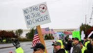 FILE PHOTO: Boeing employees and others line the street with signs and American flags as they protest the company's coronavirus disease (COVID-19) vaccine mandate, outside the Boeing facility in Everett, Washington, October 15, 2021. REUTERS/Lindsey Wasso