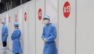 Staff members wait outside booths where people receive a vaccine against the coronavirus disease (COVID-19) at a vaccination center, during a government-organized visit, in Beijing, China, April 15, 2021. REUTERS/Thomas Peter