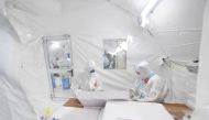 Workers in protective suits work inside a makeshift nucleic acid testing laboratory during a mass testing following local cases of the coronavirus disease (COVID-19) in Lanzhou, Gansu province, China October 25, 2021. Picture taken October 25, 2021. cnsph