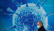 A man wearing a protective face mask walks past an illustration of a virus outside a regional science centre amid the coronavirus disease (COVID-19) outbreak, in Oldham, Britain August 3, 2020. REUTERS/Phil Noble/File Photo

